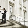 Four people stand on the stairs of a government building.