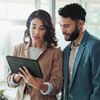 A professional looking lady showing content on her tablet to a man.