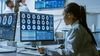 A woman in a doctor's coat looking at brain image scans.