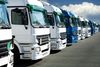 Fleet of large trucks in a parking lot.