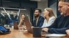 Four people sit at a conference room table.