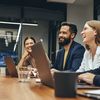 Four people sit at a conference room table.