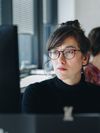 Person with glasses stares at a computer monitor.