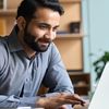 Person in gray button-down shirt works on laptop.