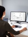 Healthcare professional reviews a document on a desktop computer. 