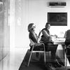 Black-and-white photo of office workers around a conference table.
