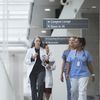 Healthcare professionals walk down a hospital hallway engaging in discussion.
