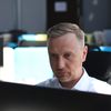 Person in white button-down shirt sits at a computer.