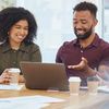 Three co-workers sit at a conference desk with coffee and a single laptop to strategize their intelligent automation strategy.