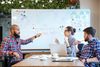 A group of young professionals having an active discussion using a whiteboard.
