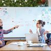 A group of young professionals having an active discussion using a whiteboard.