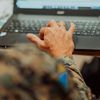 Person wearing military fatigues uses laptop computer. 