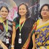 Three businesspeople wearing lanyards stand together at a Hyland office in India. 