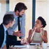 Three professionals holding work discussion in an office.
