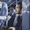 Three people collaborate in front of a desktop computer.