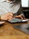 A person uses a stylus to sign a lending document on a tablet. 