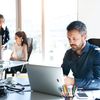 Three people work on computers in a bright modern office.