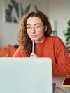 Young person sitting in front of a laptop computer at home.