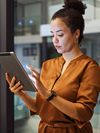 Person stands and works in an office while holding a tablet. 