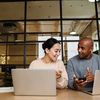 Woman and man having a discussion with laptops