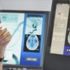 Medical professional wearing scrubs and a hair cover reviews medical images on a desktop computer.