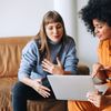 2 girls discussing and one of them holding a laptop 