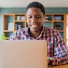 A person smiles while participating in a free, virtual cloud consultation on a laptop at home.