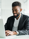 Person smiles and types on a laptop.